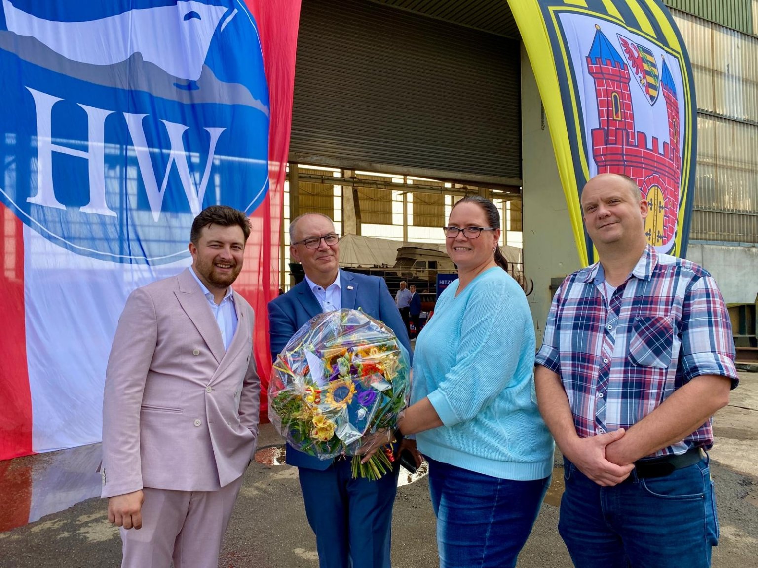 Beate und Andreas Welzel (r.) überreichen den Geschäftsführern der Hitzler Werft, Kai und Marek Klimenko im Namen der WVL einen Blumenstrauß und Glückwünsche zum Jubiläum. Die Hitzler Werft ist seit 2024 Mitglied in der WVL (Foto: Dirk Eisermann) 140 Jahre Hitzler Werft in Lauenburg